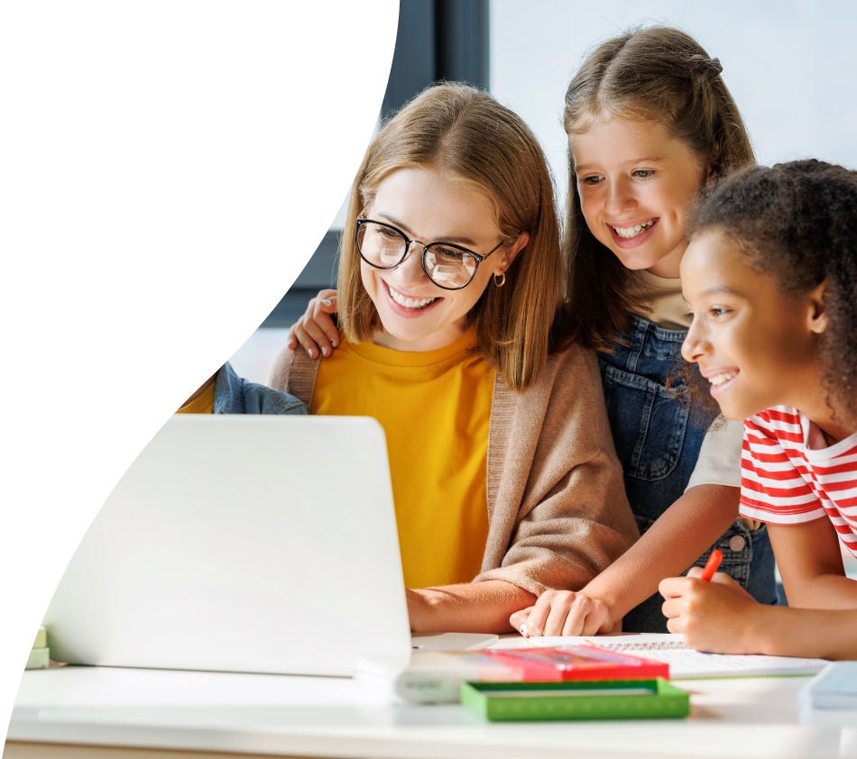 A woman with a pageboy cut and glasses looks at the screen of a laptop with a smile. Surrounding her are boys and girls of around six or seven years old, who are looking at the monitor with interest and happiness.