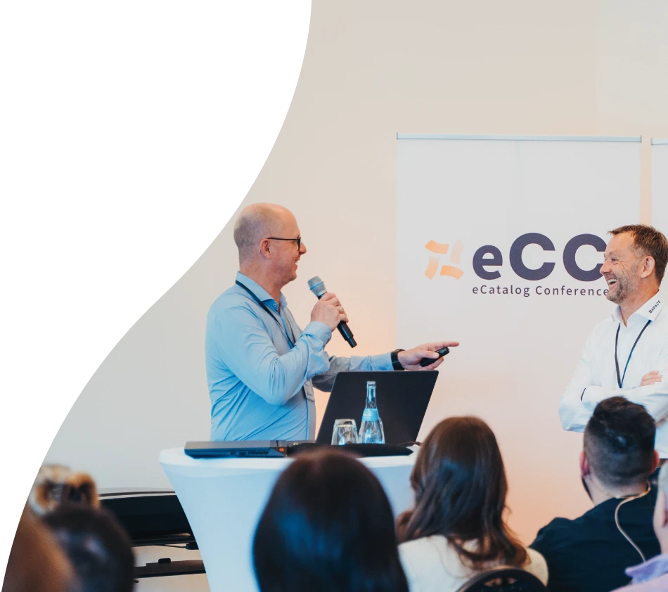 Herby Tessadri, Head of Sales at crossbase, speaks to the audience with microphone in hand. He points with his left hand to Achim Angel from 4PACE, who is giving a presentation together with him. Both laugh and look directly at each other.