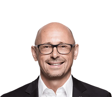 Günther Rossdeutscher, Managing Partner at asecos, looks friendly into the camera. He is wearing dark glasses, a white shirt and a dark jacket. He is bald with a short beard.