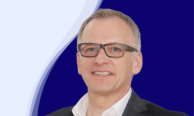 Wolfgang Maier, directeur marketing chez LEUCO, regarde aimablement la caméra. Il porte des lunettes noires marquées, une chemise blanche à col ouvert et une veste sombre. Ses cheveux courts sont grisonnants.
